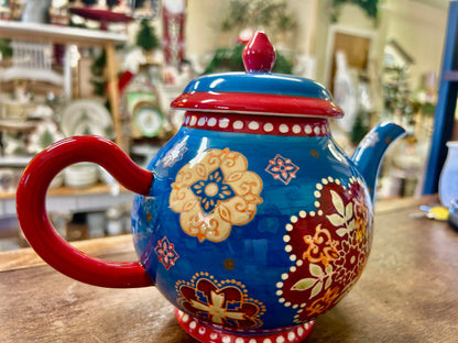 Blue ceramic tea pot with red handle, domed lid, and folk floral pattern