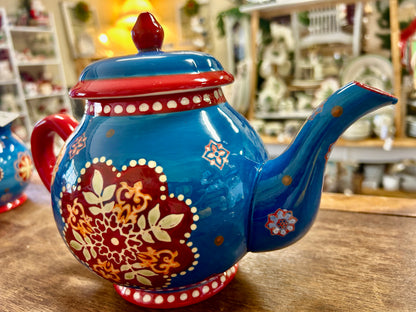 Blue ceramic tea pot with red spout, domed lid, and ornate floral motifs