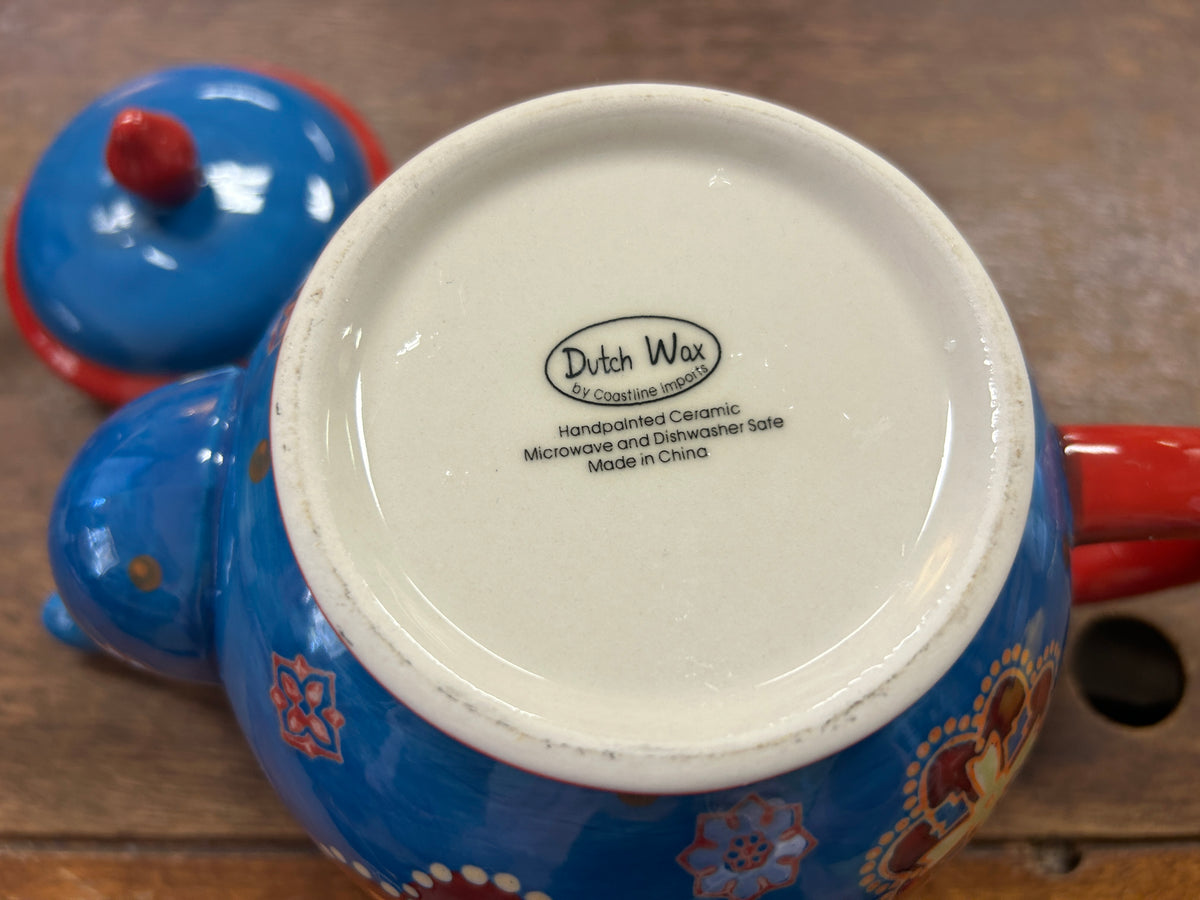Bottom of blue ceramic tea pot labeled Dutch Wax, handcrafted, made in China