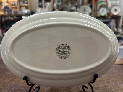 Oval white porcelain gravy plate bottom with maker stamp and black display stand