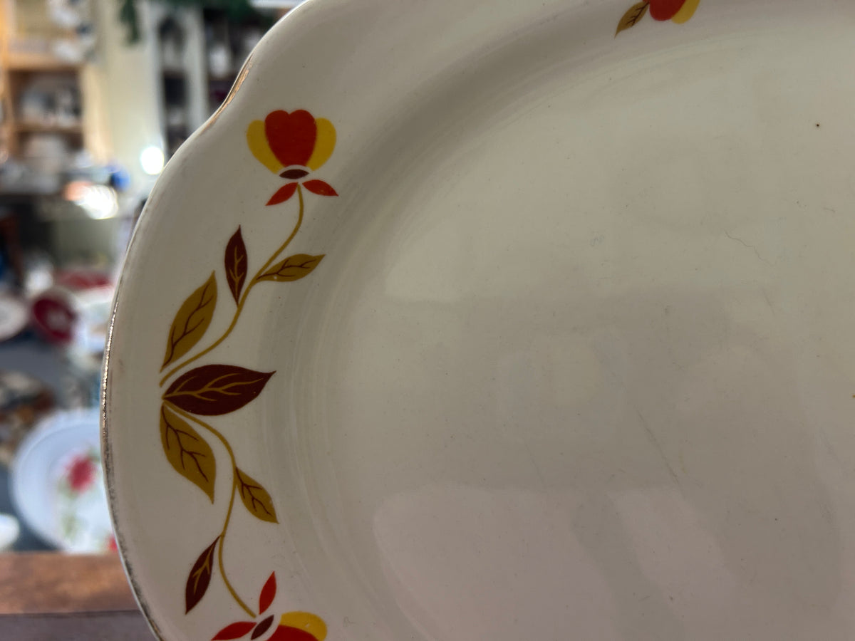 White ceramic platter with multicolor leaf-and-berry pattern along the rim