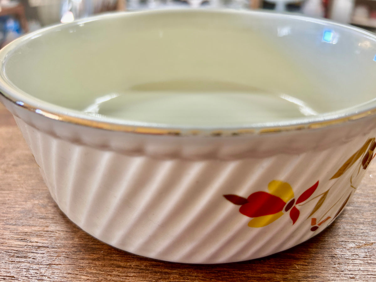 Ceramic souffle bowl with multicolor fall leaves on cream exterior and gold rim