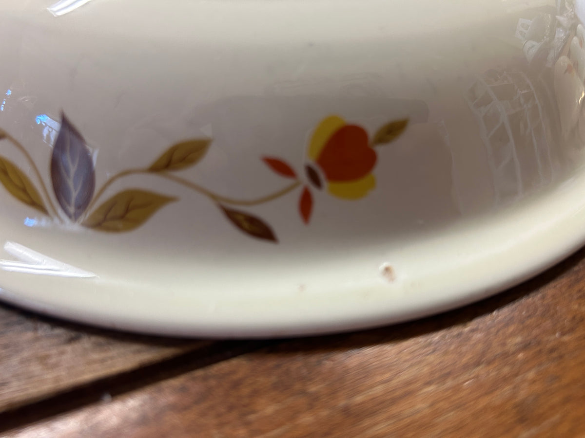 Close-up of white ceramic rim with colorful autumn flower and leaf decoration