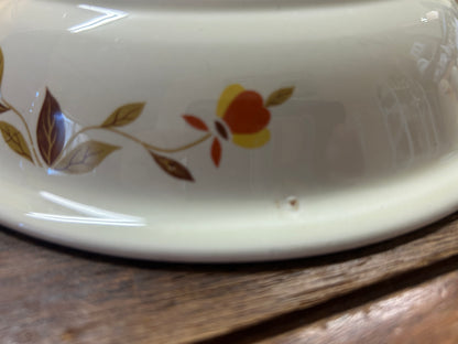 Close-up of white ceramic rim showing orange flower and brown leaf accents
