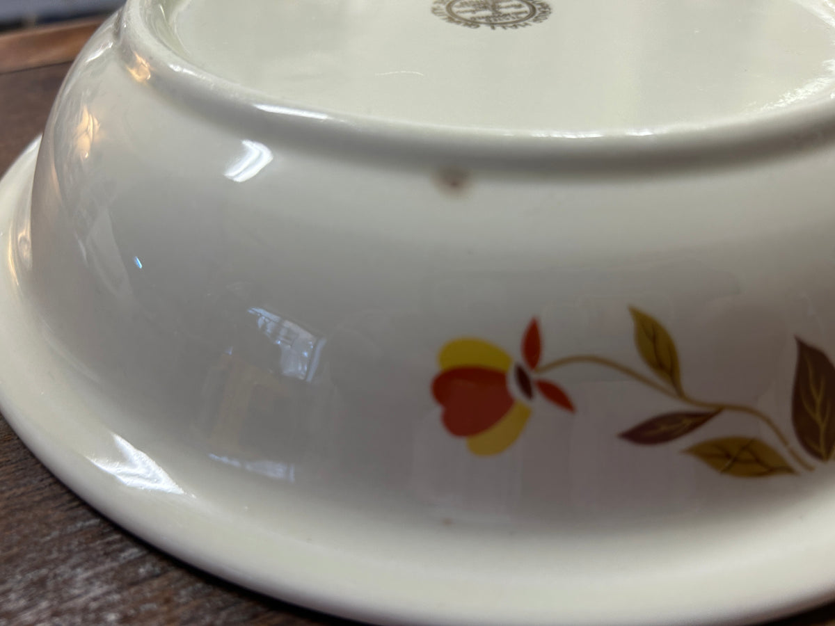 Close-up of white ceramic pie plate edge with fall floral decal in red, yellow, and brown
