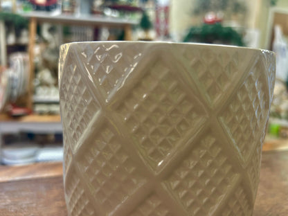 Cream planter pot showing its raised diamond pattern and open rim.