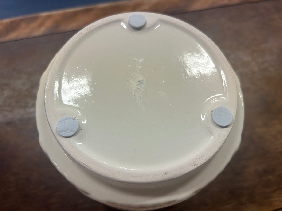 Cream planter pot base with three raised feet.