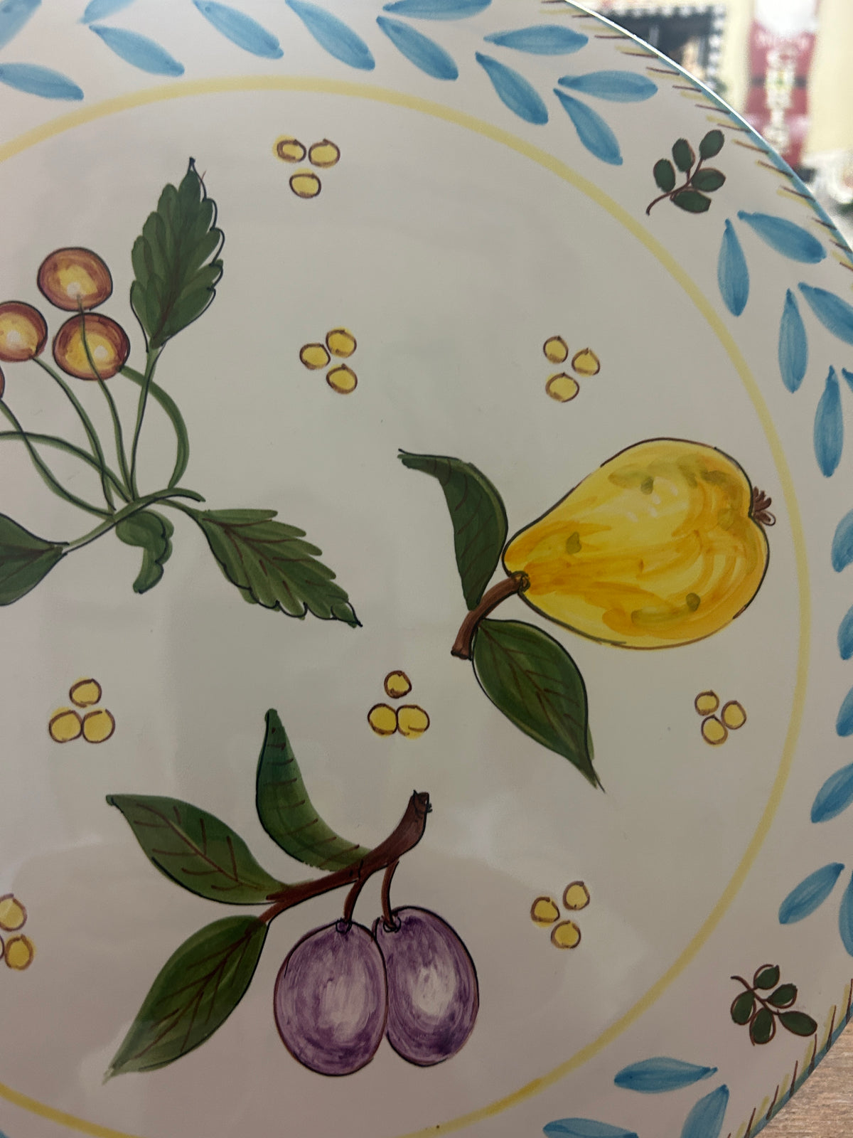Close-up of platter with painted yellow pear, purple plums, and leaves