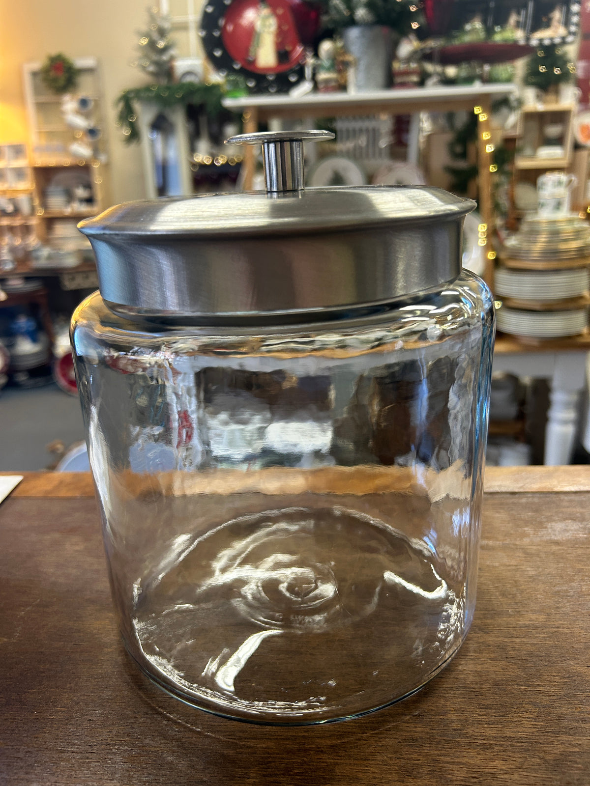 Clear glass canister with a brushed metal lid and raised knob