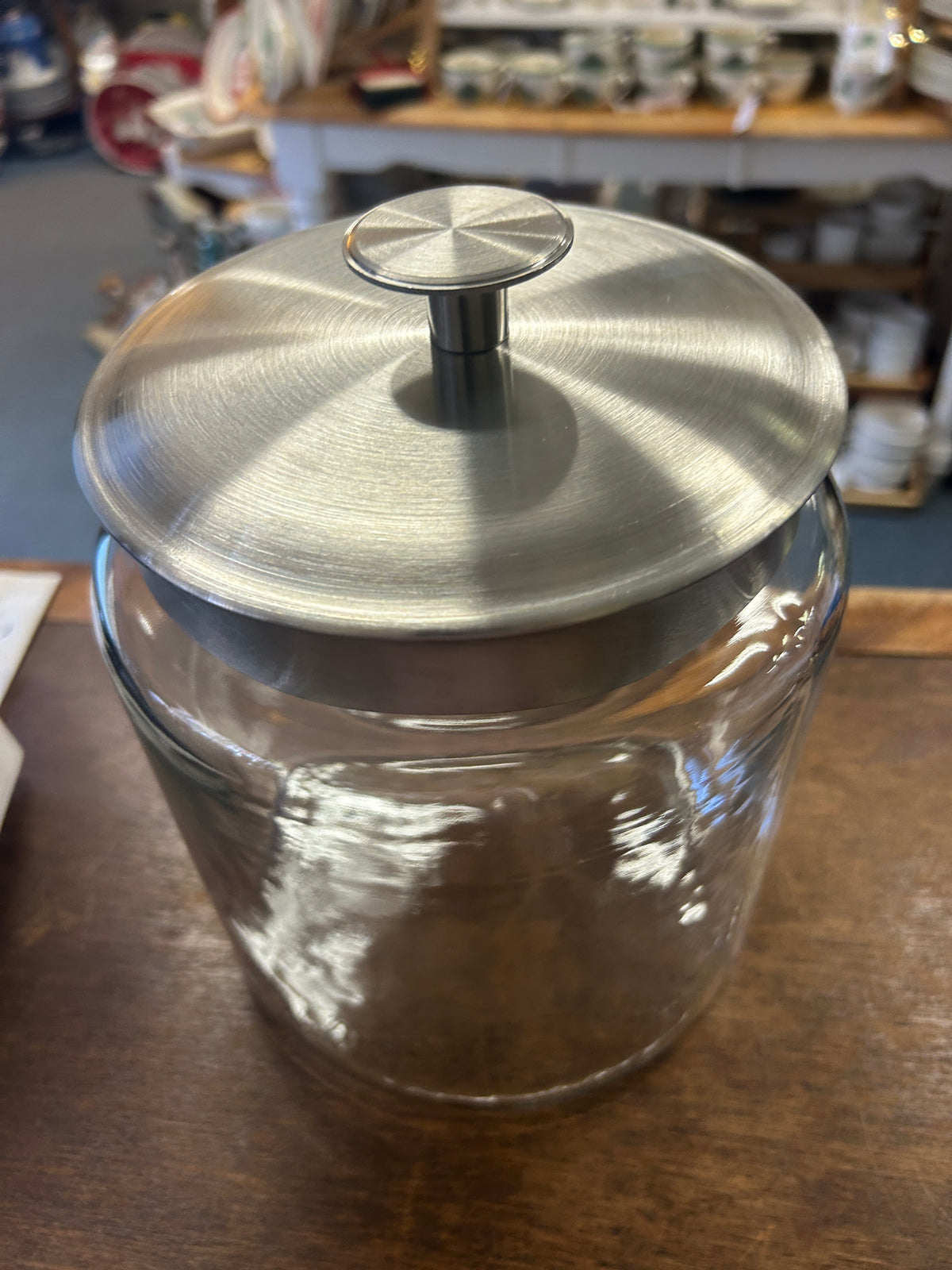 Clear glass canister viewed from above, showing its round metal lid and knob