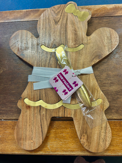 Gingerbread-shaped wooden serving board with gold accents and a wrapped spreader