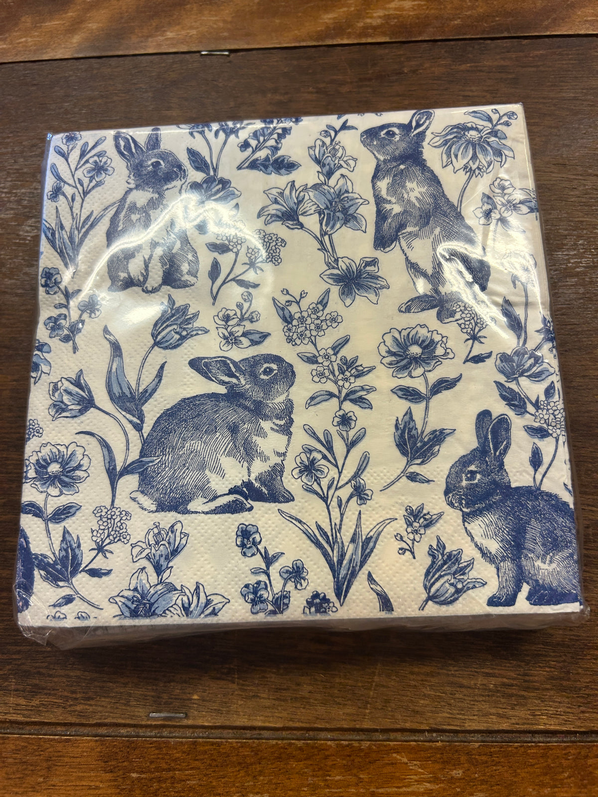 Blue and white paper napkins with a repeating rabbit and floral print.
