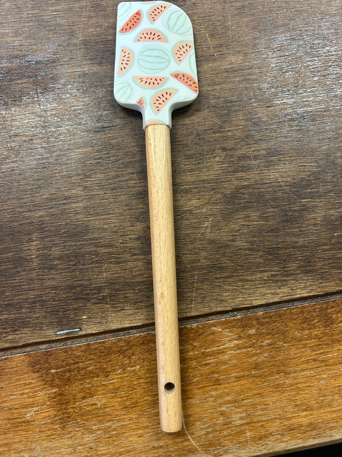 Watermelon scraper with a pale aqua head, pink melon pattern, and wooden handle