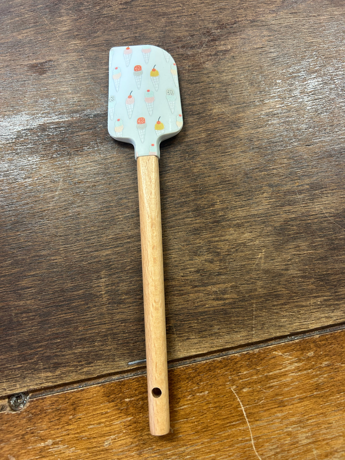 Ice cream scraper with a pale blue dessert-print silicone head and wooden handle