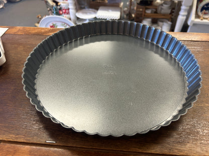 Round silver tart pan with a removable base and fluted sides