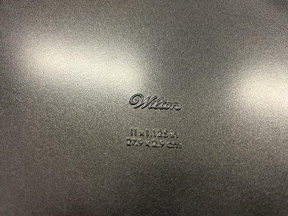 Close-up of Wilton branding and 11 x 1.125 inch size marking on the pan base