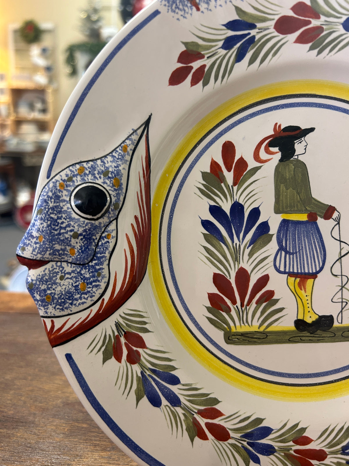 Quimper fish-shaped plate detail with painted fish head, floral motifs, and central figure