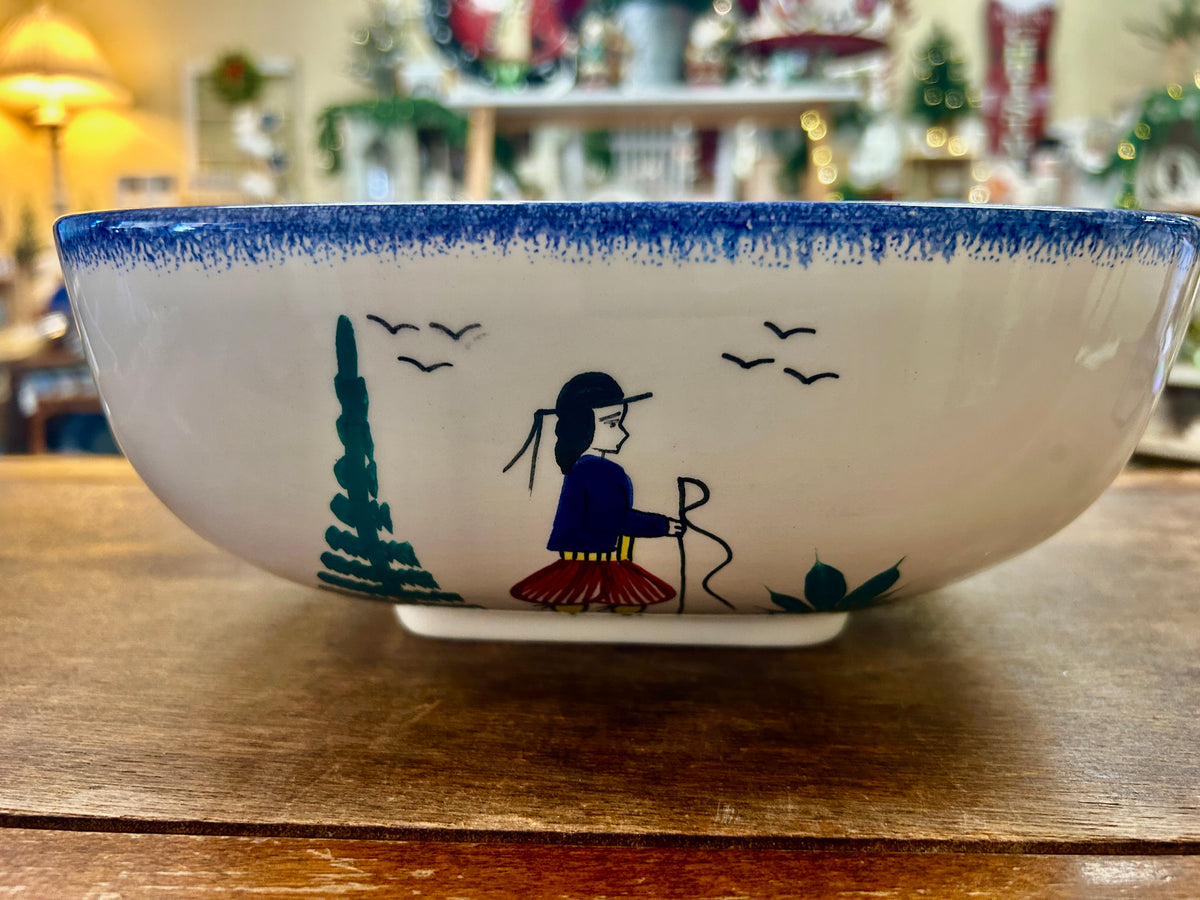 Quimper serving bowl with a painted figure, tree, birds, and blue rim