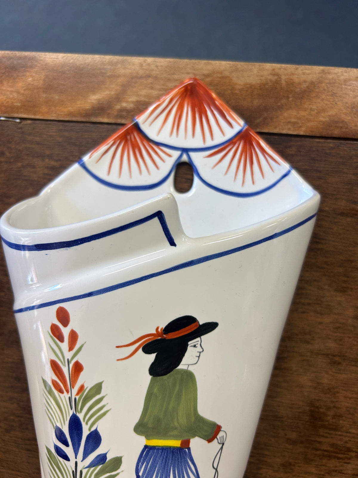 Quimper wall pocket vase with a painted figure and red-striped hanging loop