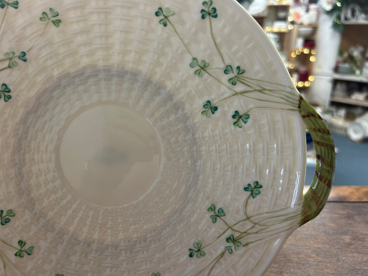 Close-up of a green handle and shamrock vines on the cream Belleek platter