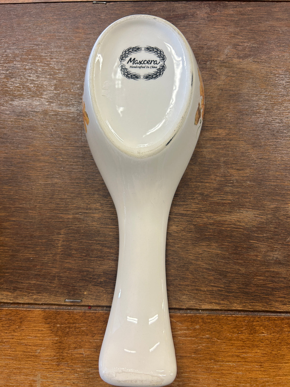 White ceramic spoon rest with Maxcera logo on back, teardrop spoon shape