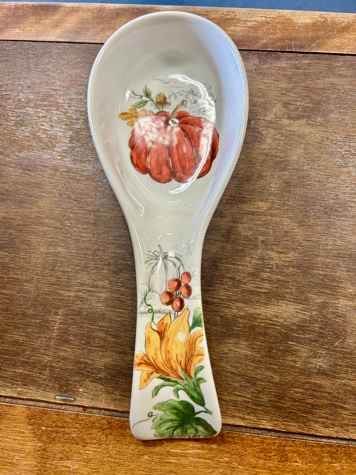 Orange pumpkin-themed spoon rest with illustrated autumn gourds on white ceramic