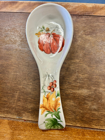 Orange pumpkin-themed spoon rest with illustrated autumn gourds on white ceramic
