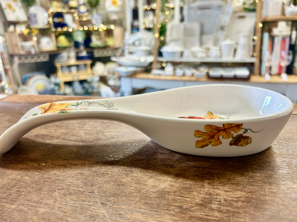 White ceramic spoon rest dish, side view, with orange pumpkin and floral accents