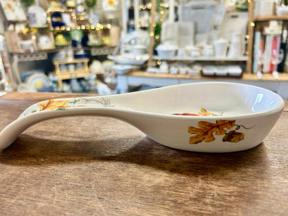 White ceramic spoon rest dish, side view, with orange pumpkin and floral accents