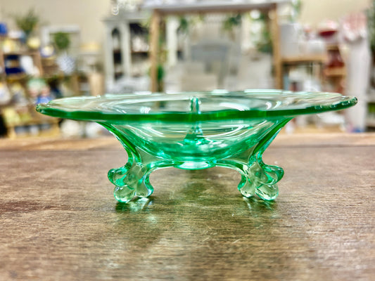 Green glass dolphin stand with shallow Empress tray on three raised legs
