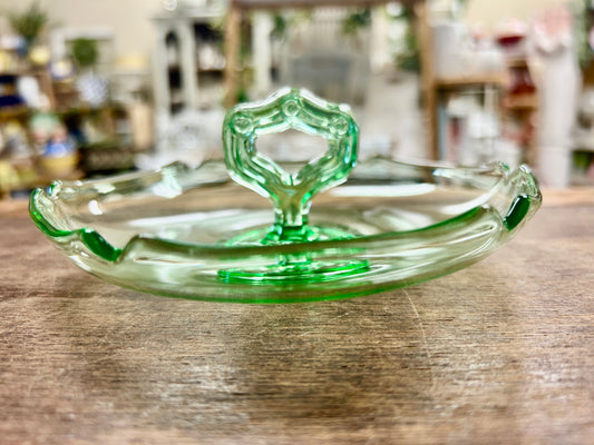 Green glass bowl with center handle detail and scalloped rim