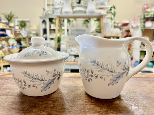 Ceramic sugar bowl with lid and matching cream pitcher, blue floral design
