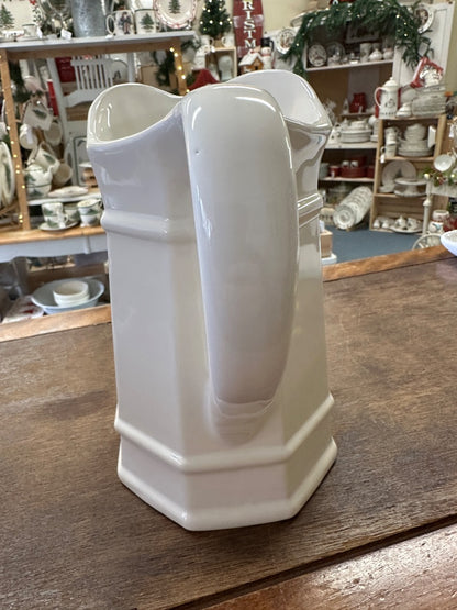 White ceramic pitcher with tall spout, curved handle, and banded design