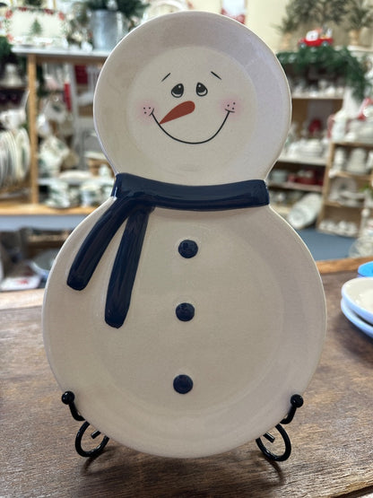 Snowman-shaped ceramic plate with blue scarf and smiling face on metal stand