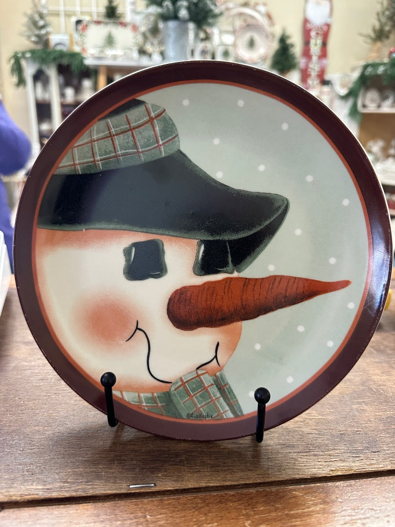 Multicolor snowman face plate with brown hat and orange carrot nose on display stand