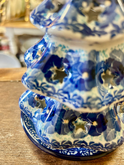 Blue ceramic tree luminary close-up with swirl pattern and arched cutout openings