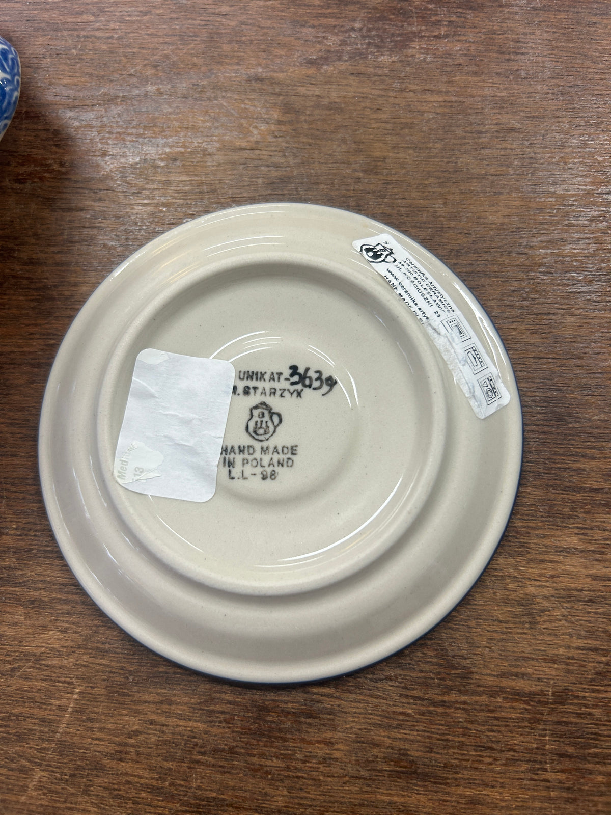 White ceramic base plate underside with UNIKAT stamp and handmade label