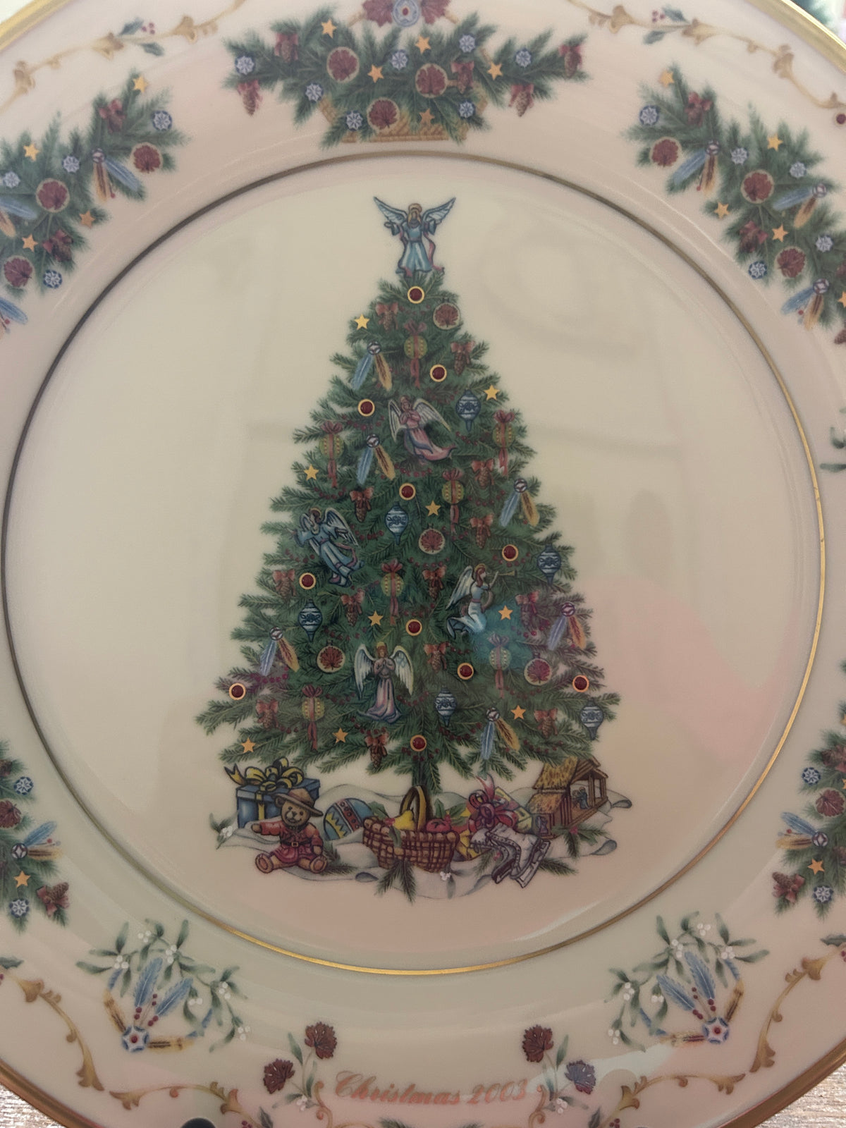 Christmas plate with painted evergreen tree, gifts below, gold rim and festive floral border