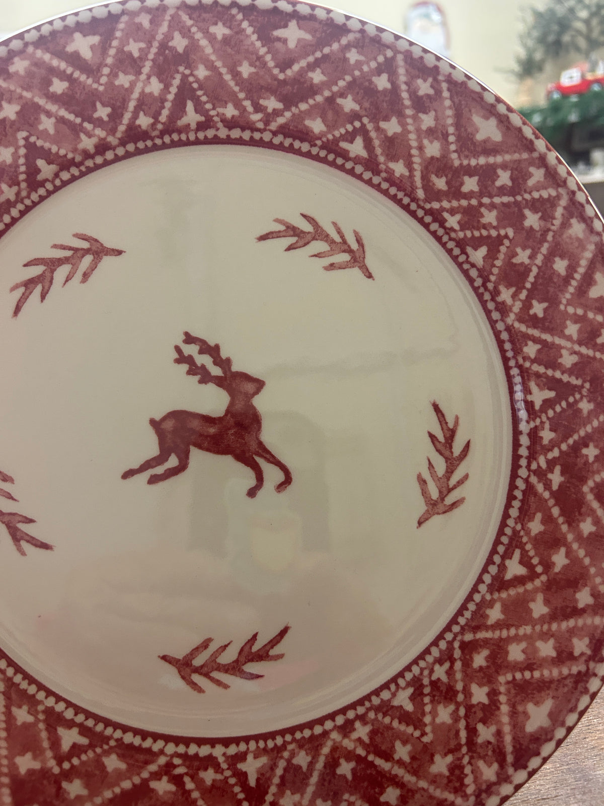 Cream dinner plate featuring red reindeer and branches, surrounded by geometric knit rim