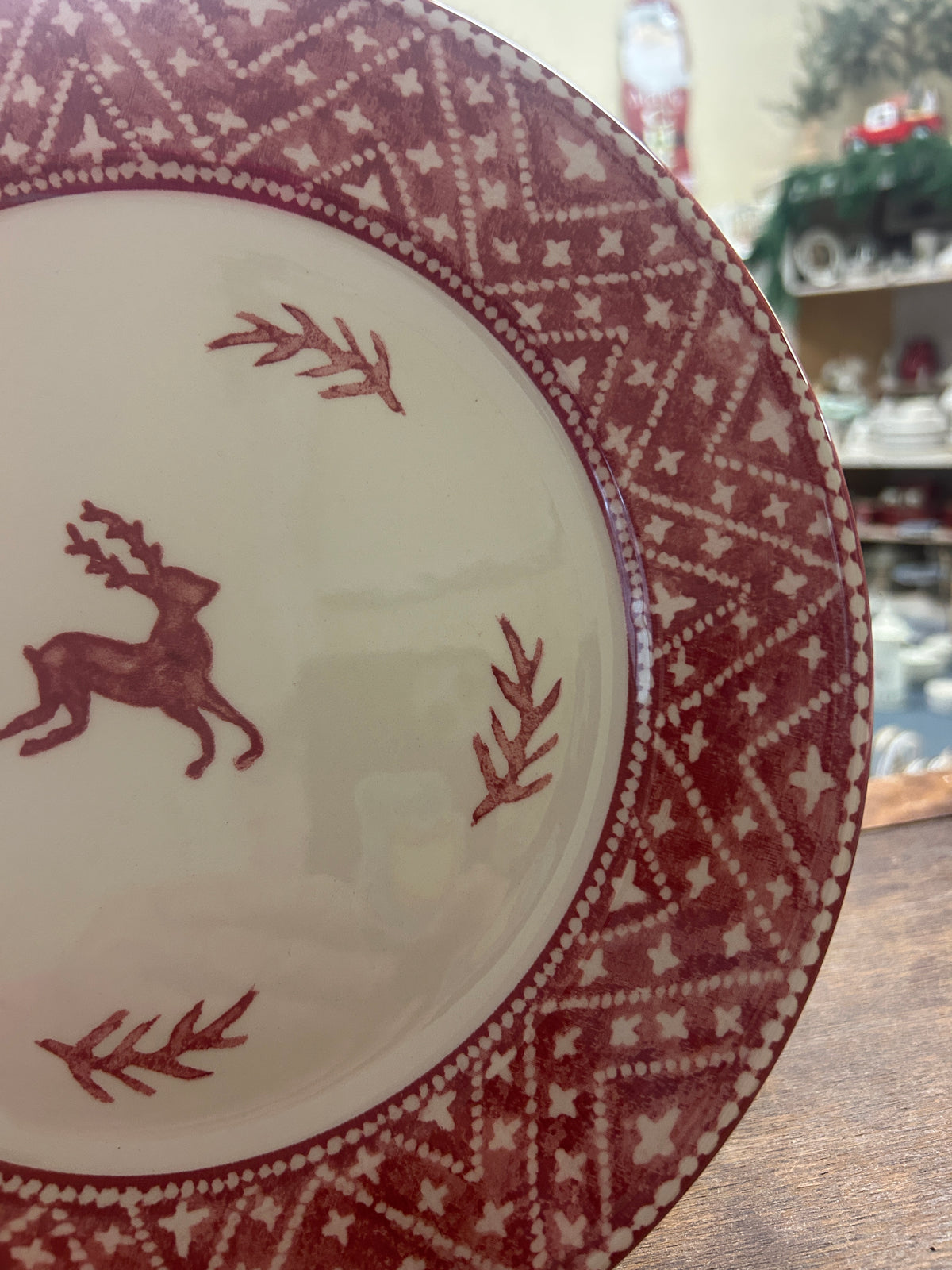 Cream dinner plate with red reindeer, branches, and diamond knit design along rim