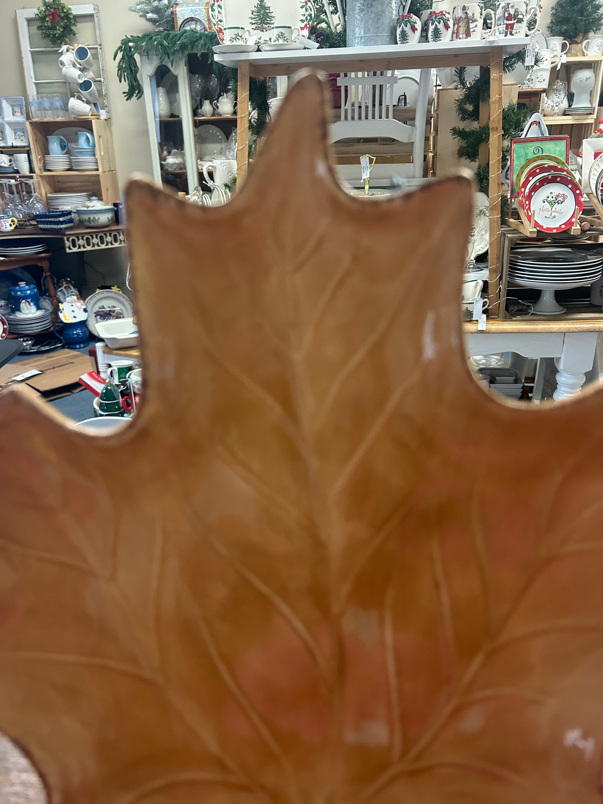 Brown leaf-shaped ceramic serving plate on black stand pegs, angled