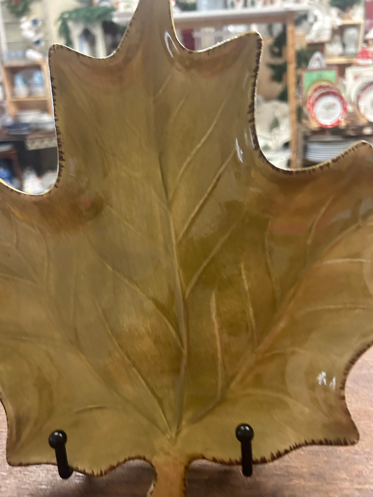 Gold-green leaf-shaped ceramic plate with glossy leaf-vein texture, close-up view