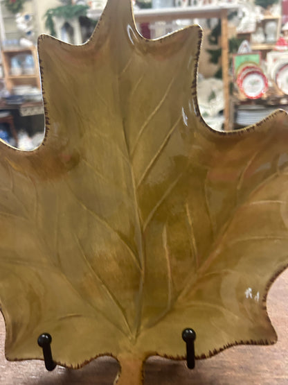 Gold-green leaf-shaped ceramic plate with glossy leaf-vein texture, close-up view