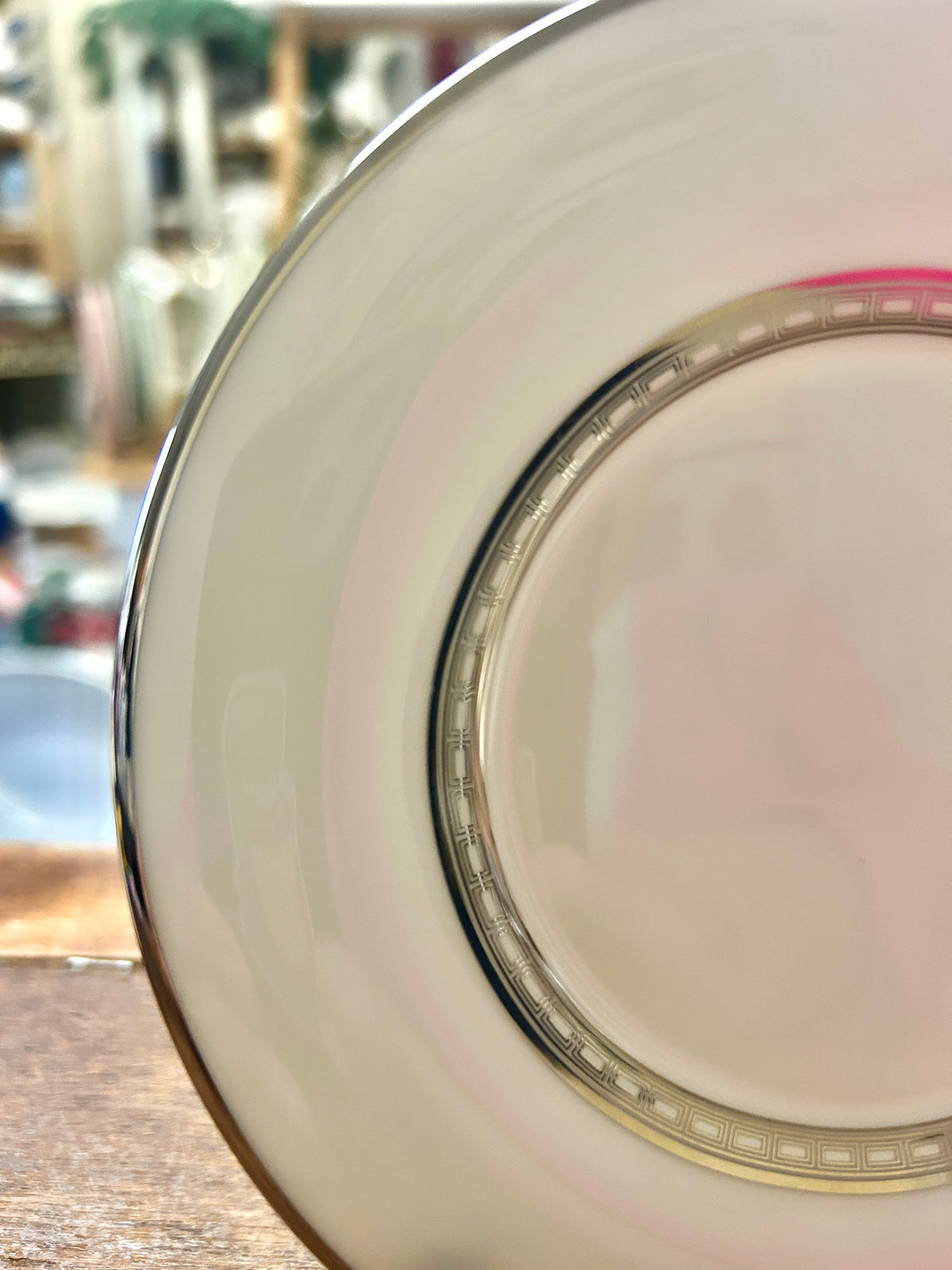 Close-up of white saucer plate rim with gold detailing and multicolor band