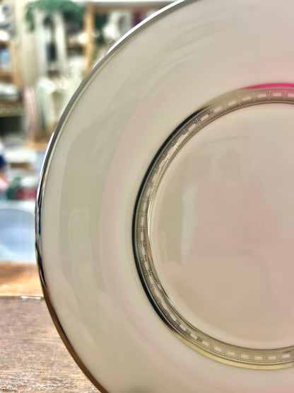 Close-up of white saucer plate rim with gold detailing and multicolor band