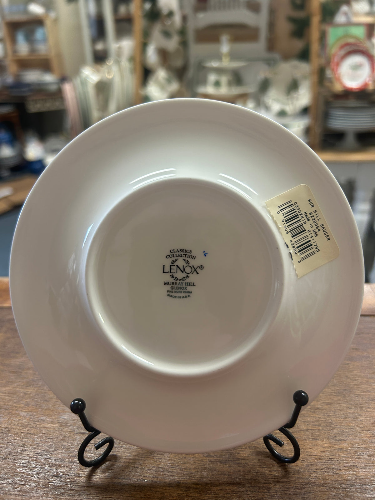 White saucer plate bottom with Lenox stamp and barcode, on black stand