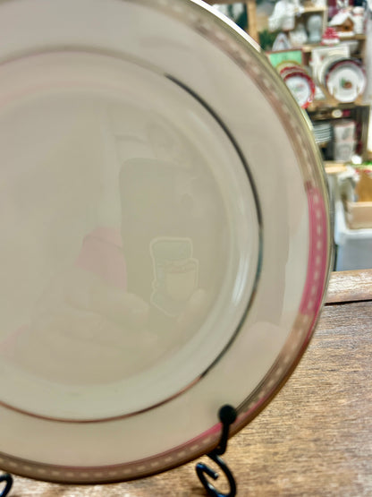 Cream bread plate on stand with silver rim, pink band, and black edge line