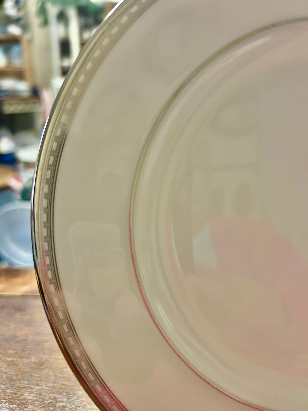 Side view of cream salad plate with silver rim and thin red edge trim