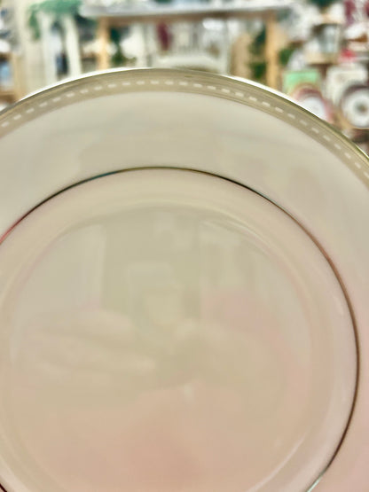 Close-up of cream salad plate with dark inner ring and silver-toned rim