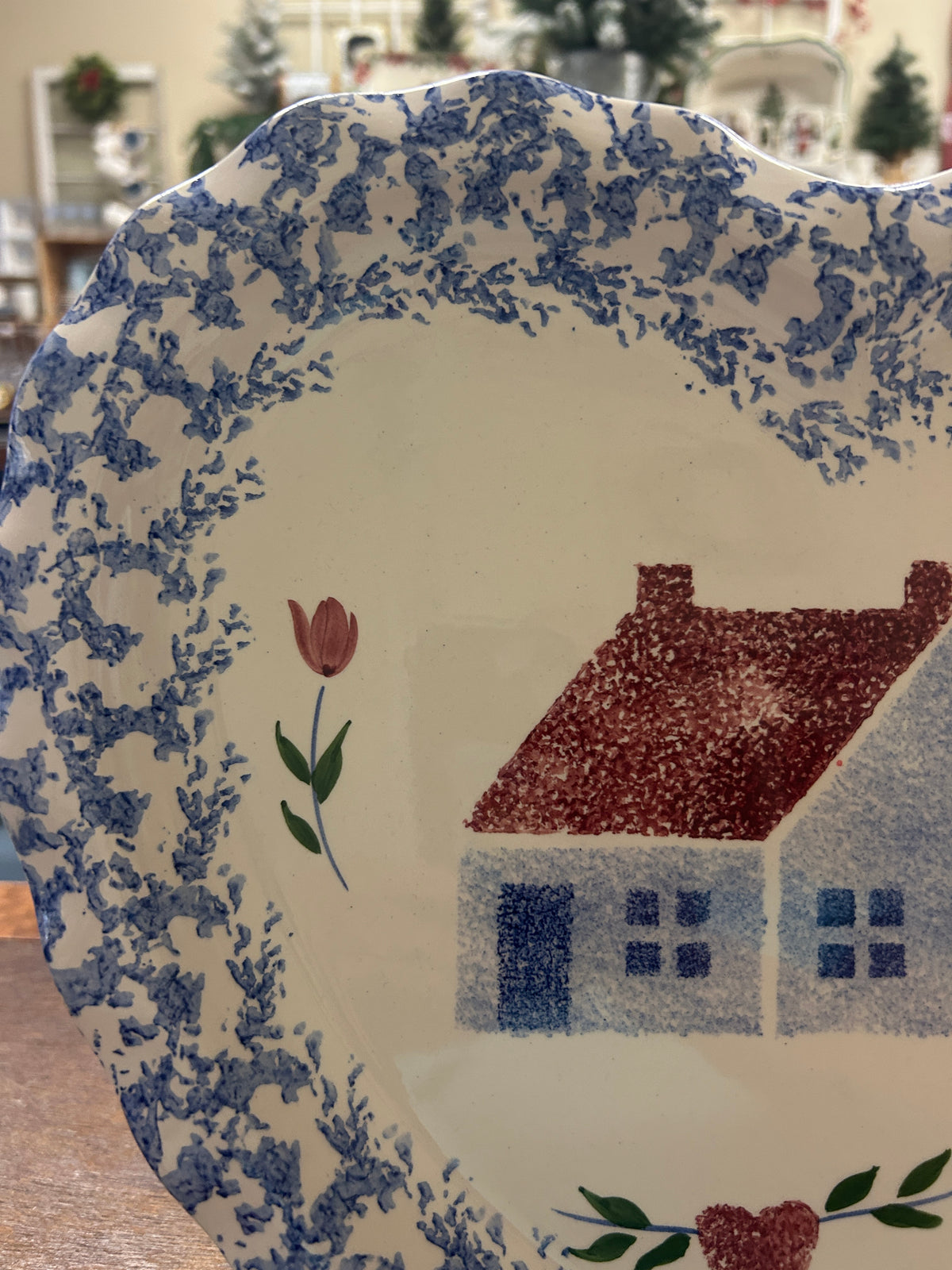 Heart-shaped platter close-up of blue speckled border, tulip stems, and red house.